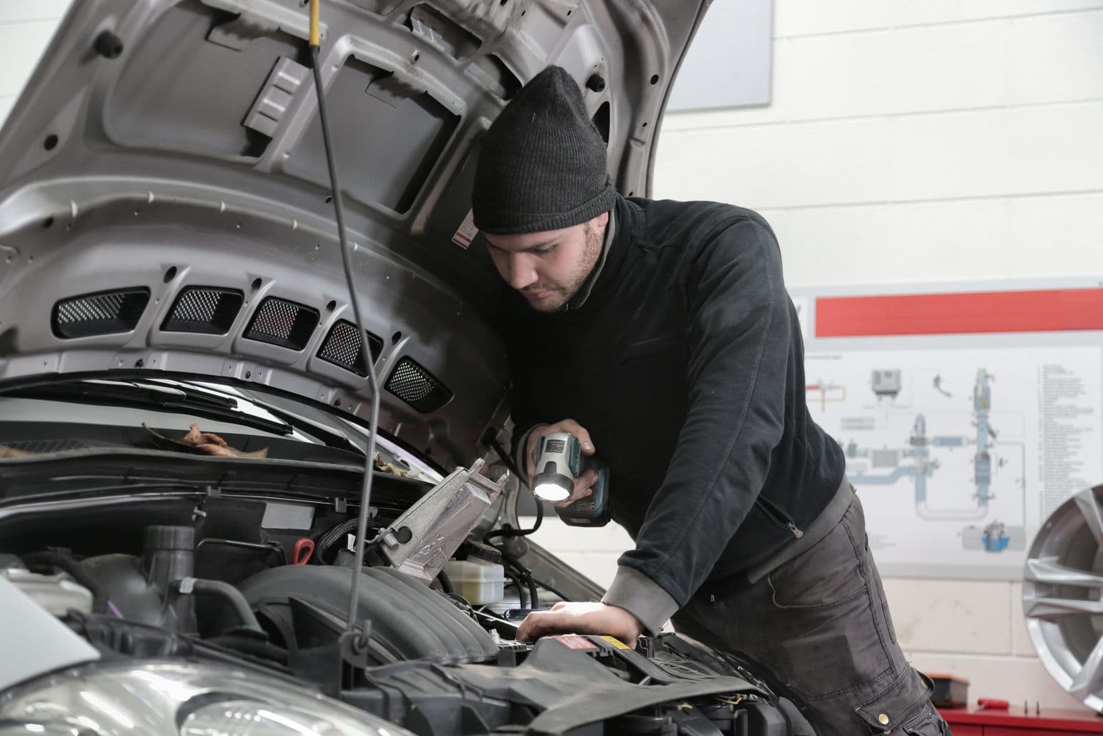 Mechanic inspecting an engine bay with an inspection lamp in a workshop